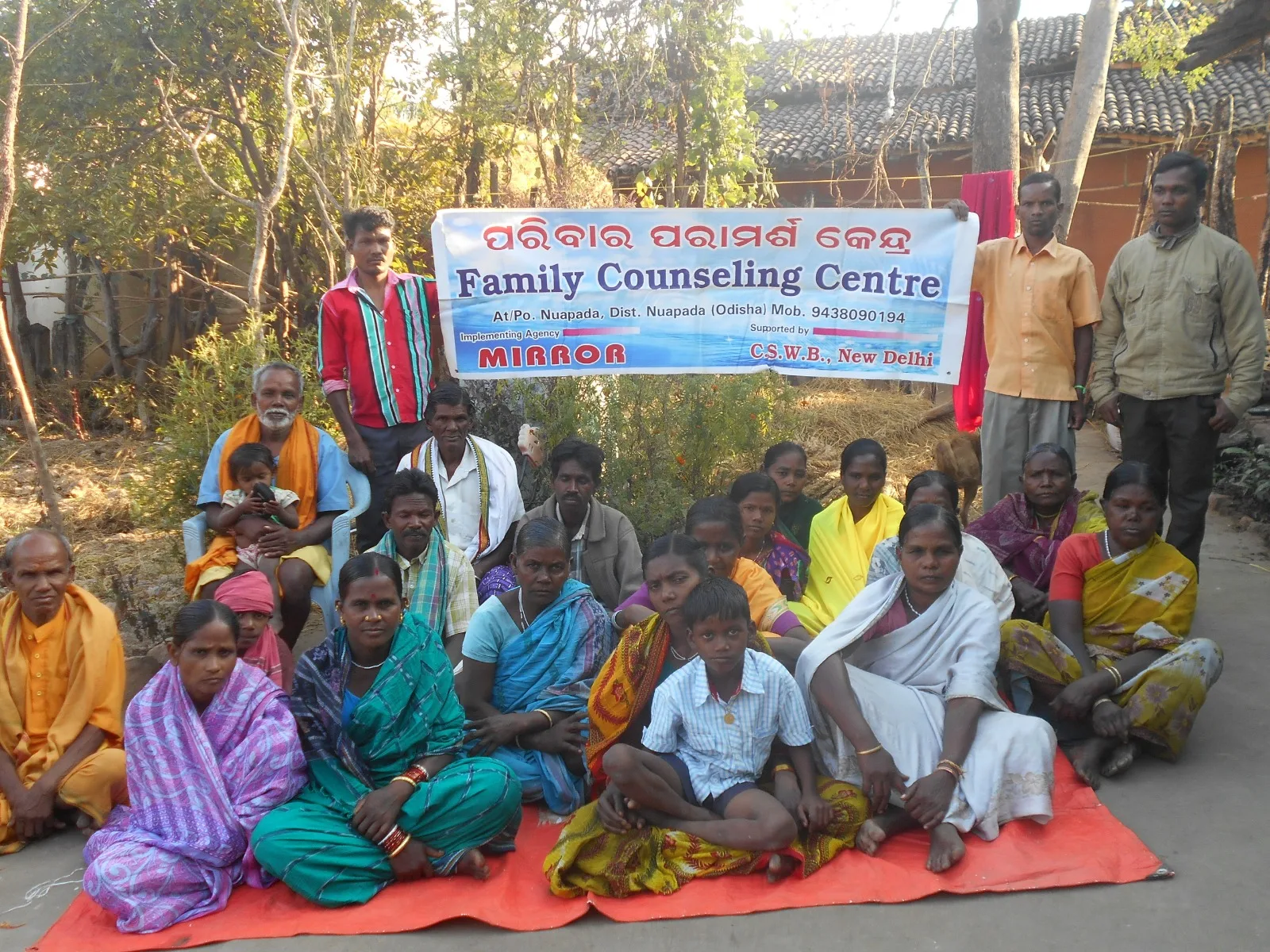 Families gathered behind a Family Counselling Centre banner